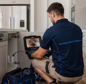 Plumber clearing a blocked toilet in a Glebe bathroom